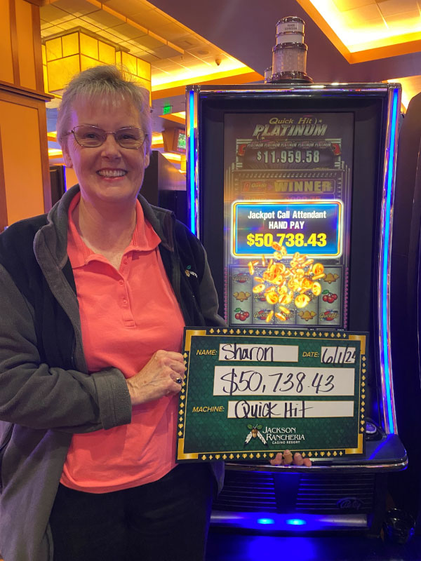 Photo of mature women standing next to a slot machine while holding a large display check for $50,738.43